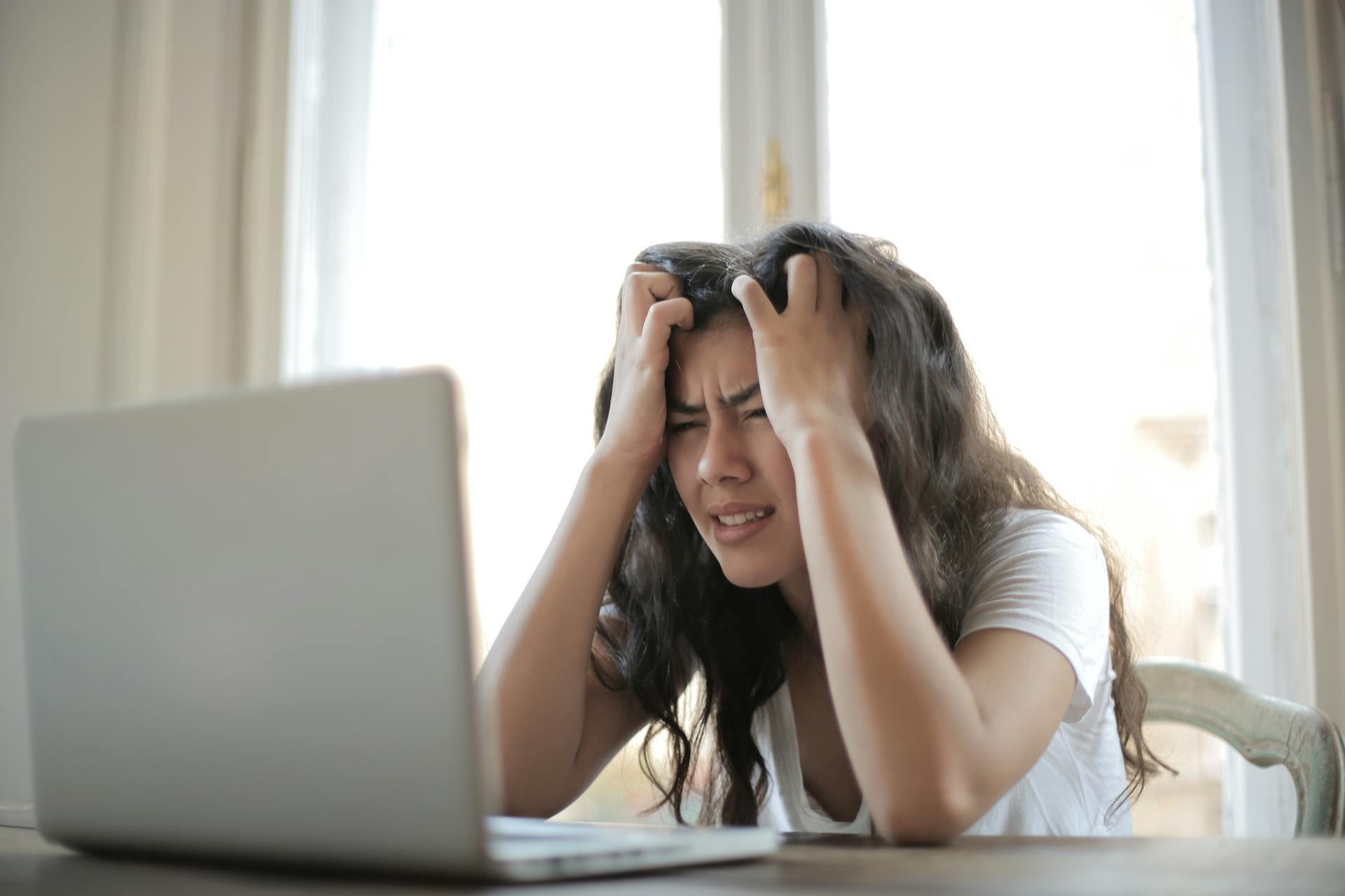 Girl holding hear head in hands, sat at desk