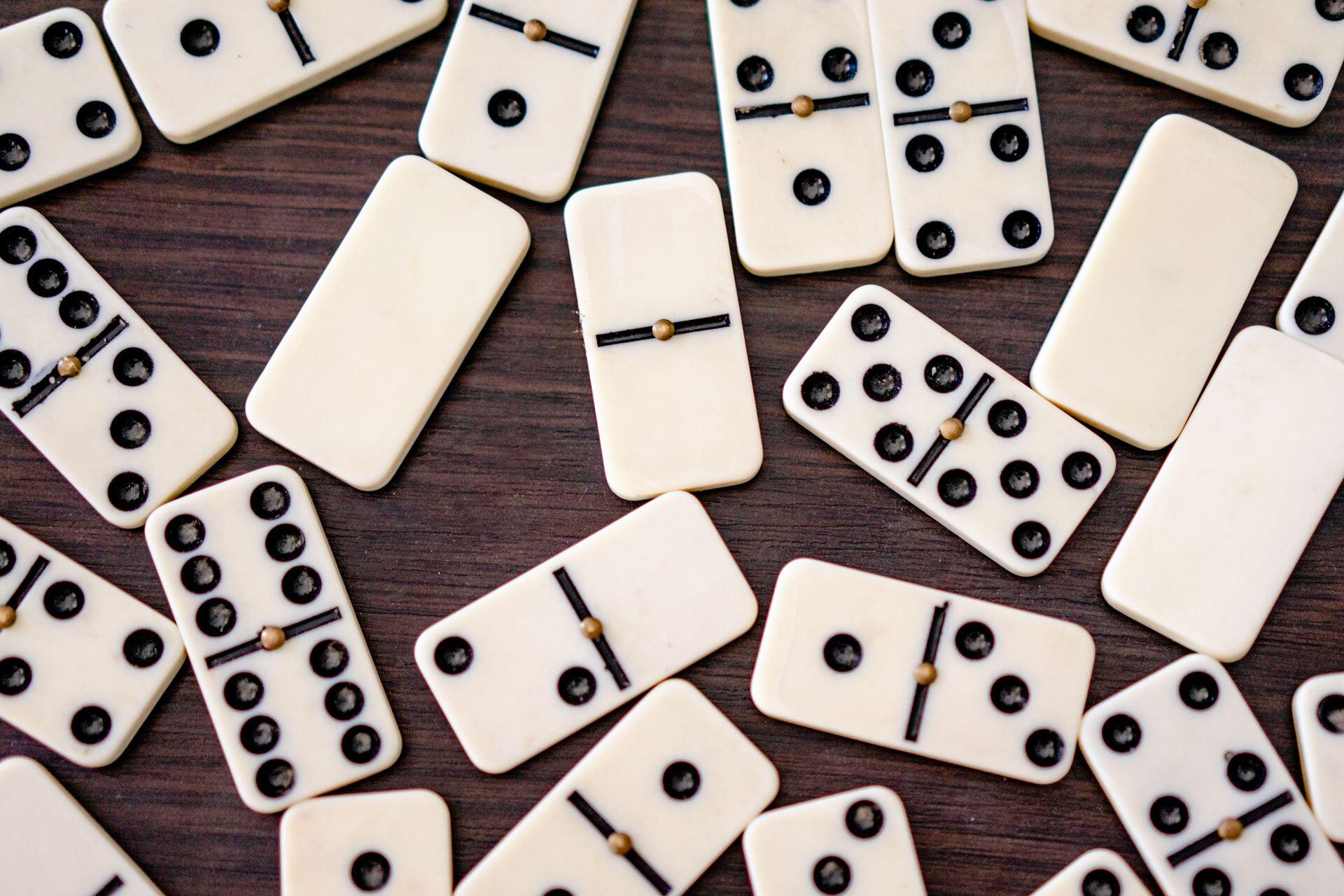 Koyu ahşap bir yüzey üzerinde dağılmış beyaz domino taşları.